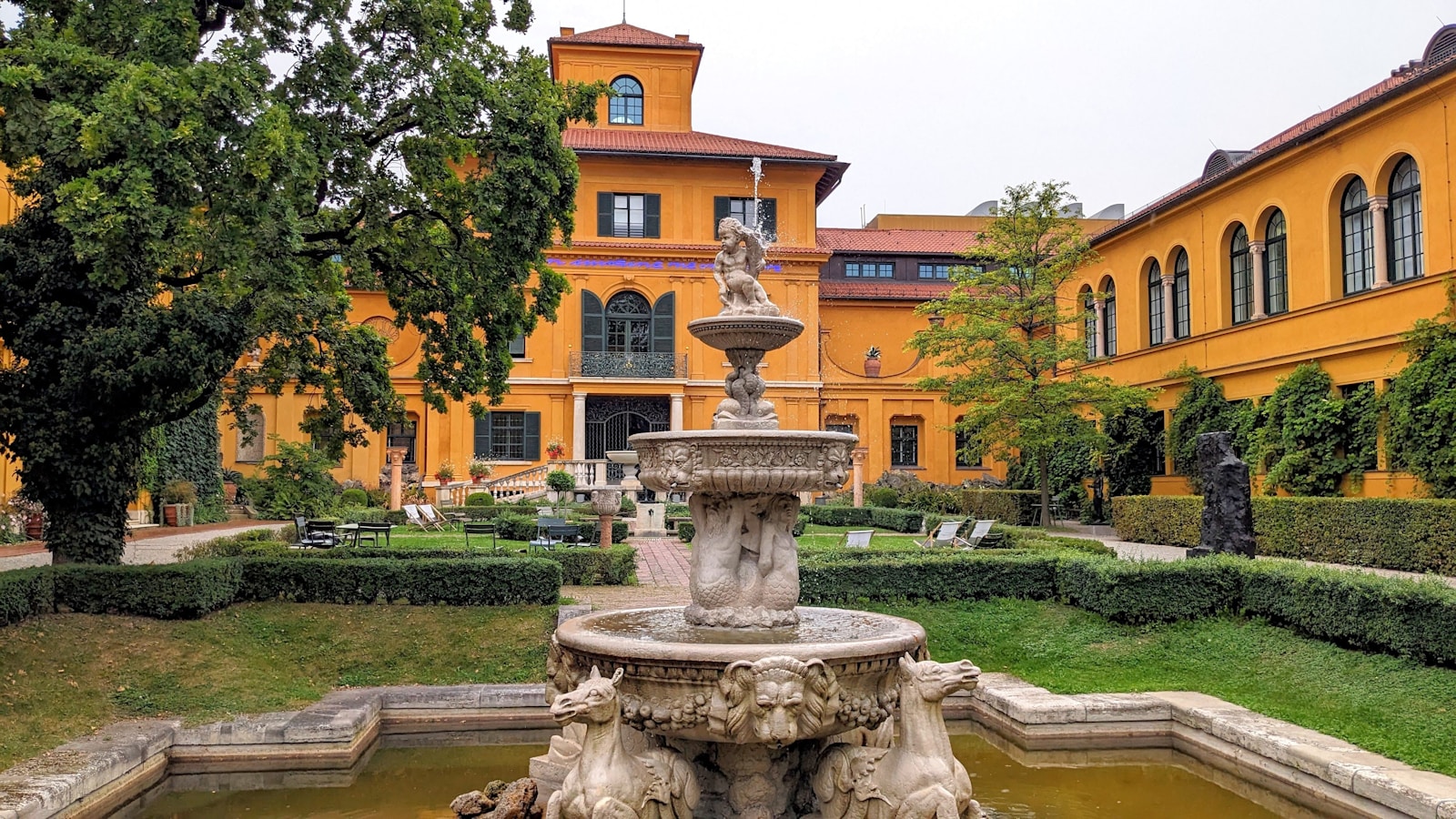 A fountain in front of a large yellow building