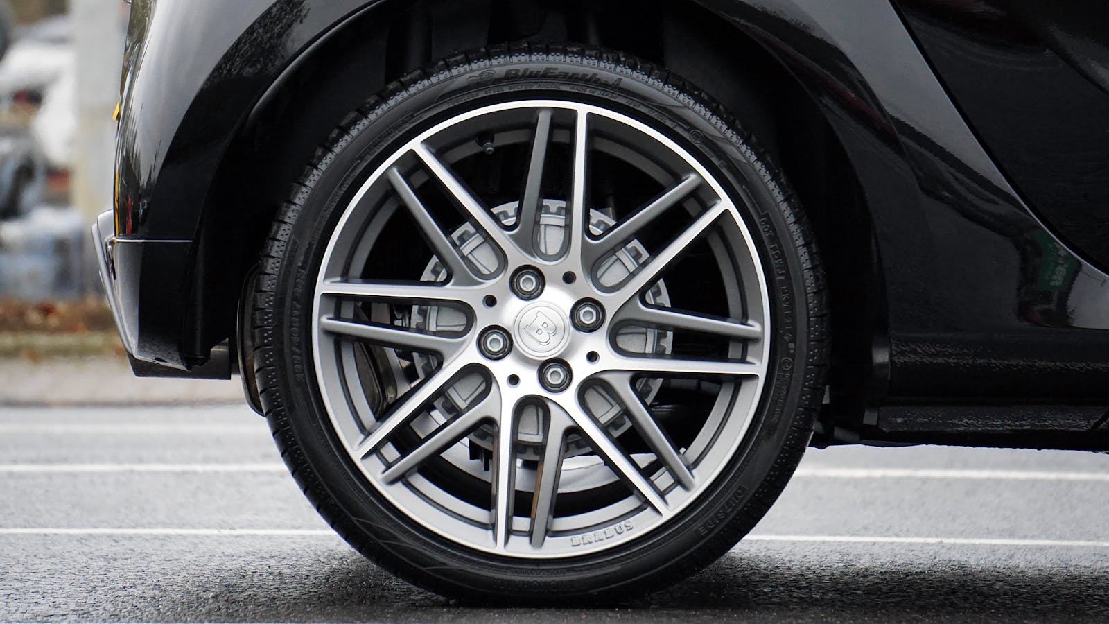 Detailed shot of a sleek car wheel and rim on a black vehicle, showcasing automotive design.